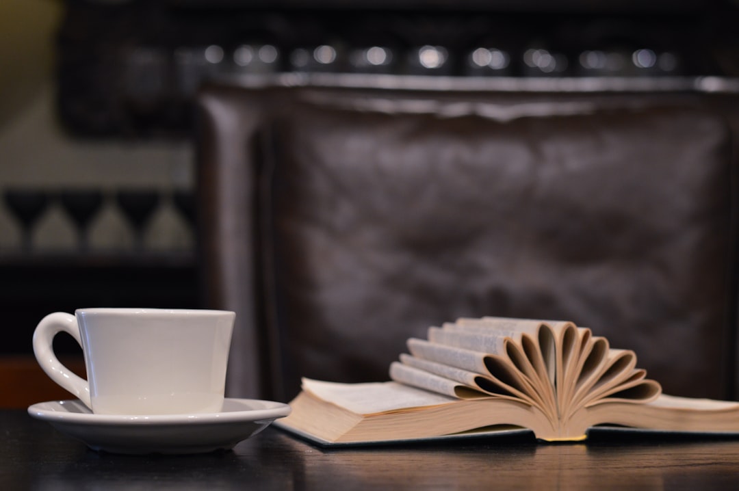 a book with decorative folds on a desk next to a white coffee cup